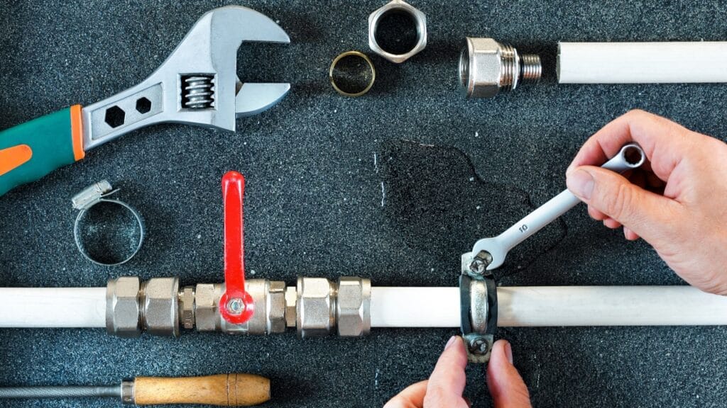 Plumber repairing a pipe valve with an adjustable wrench in Deerfield Beach