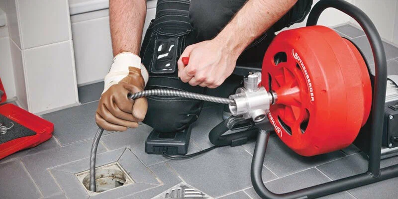 Plumber using a drain-cleaning machine in Deerfield Beach