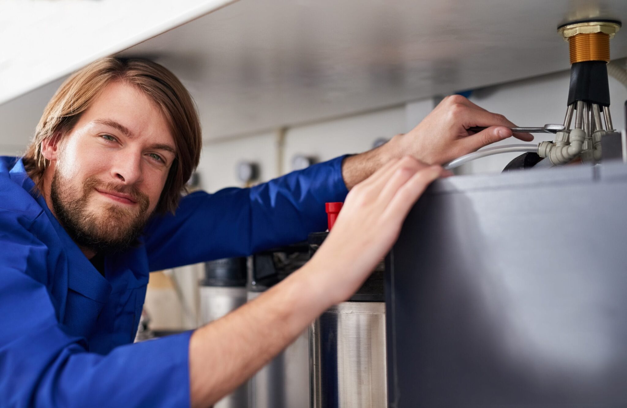Technician servicing a residential water heater tank in Deerfield Beach